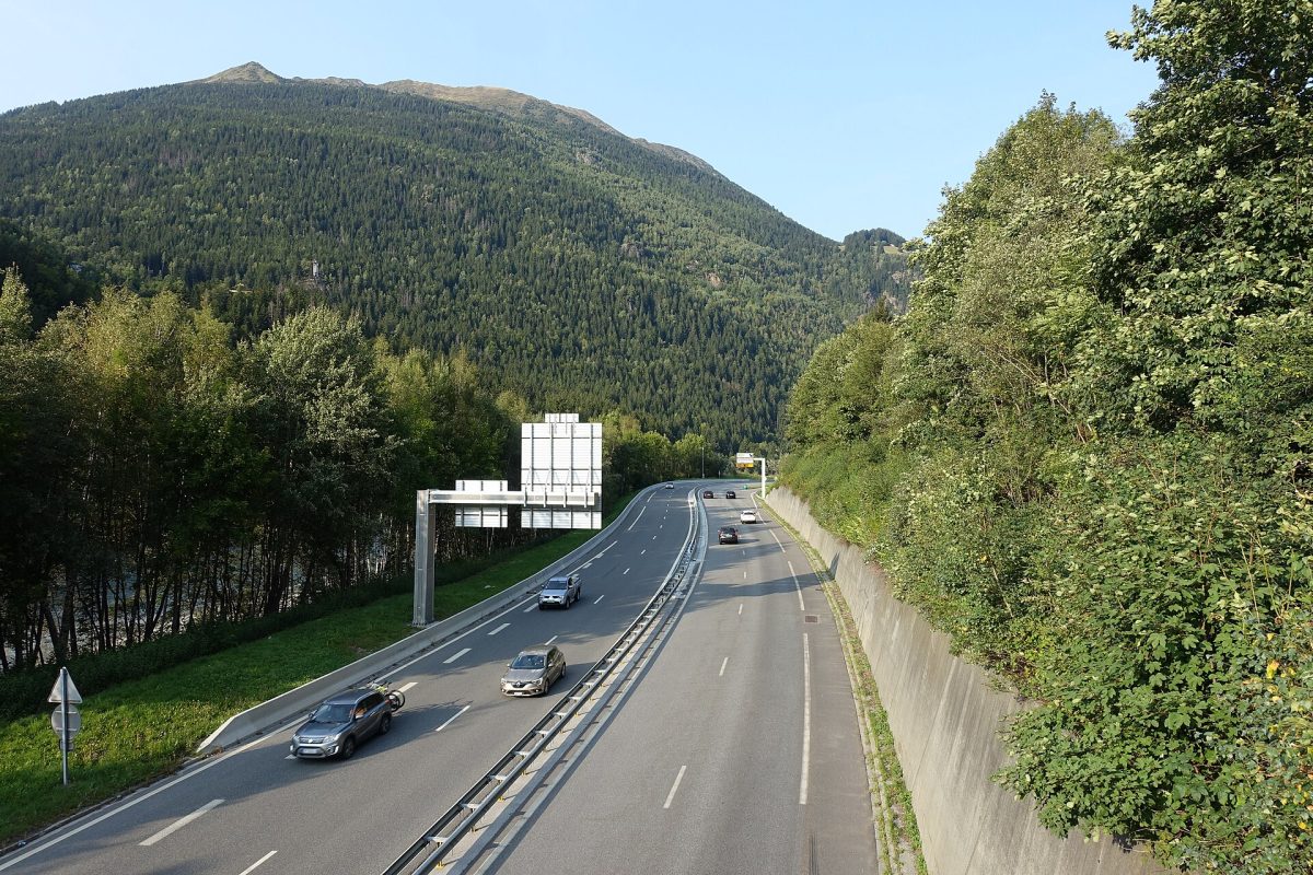 Une route de vallée alpine bordée de massifs boisés, dans les Alpes du Nord